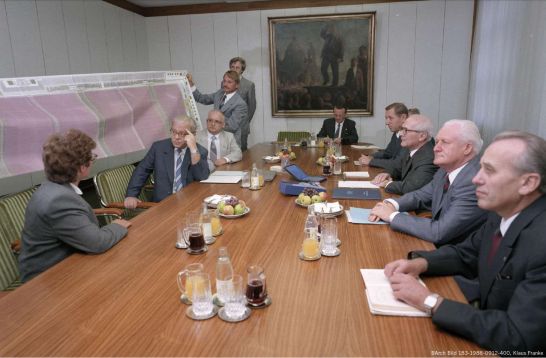 Bernd Junghans (3.v.l.) und Jens Knobloch (4.v.l.) präsentieren dem Politbüro um Erich Honecker und Günter Mittag (2.v.r.) den Schaltkreisplan des U61000.