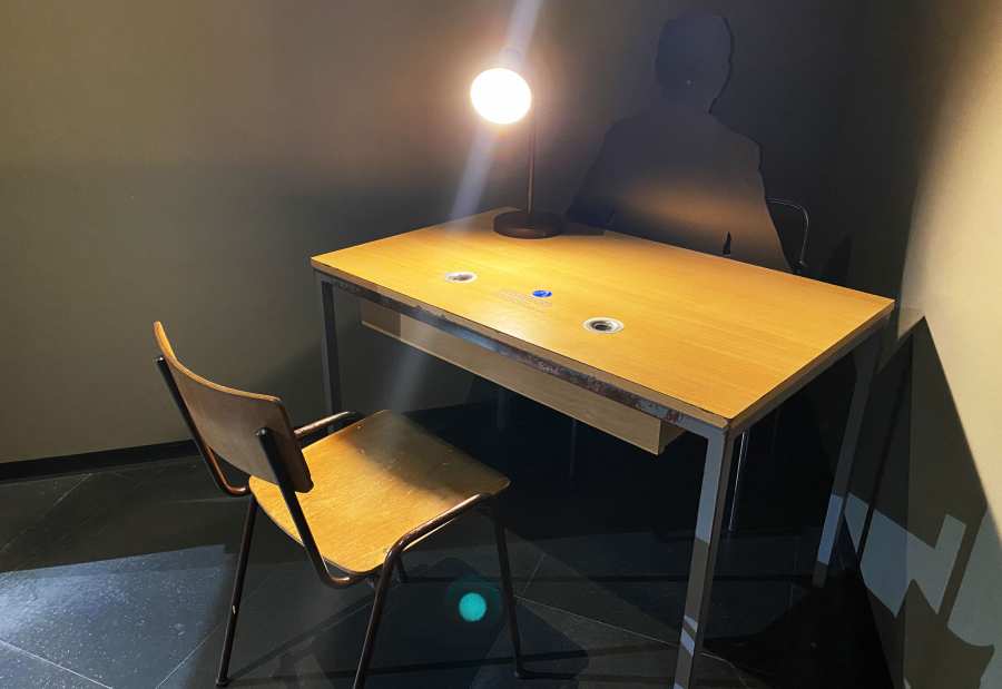 Reconstructed interrogation room of the DDR Museum with a chair, a desk and a lamp