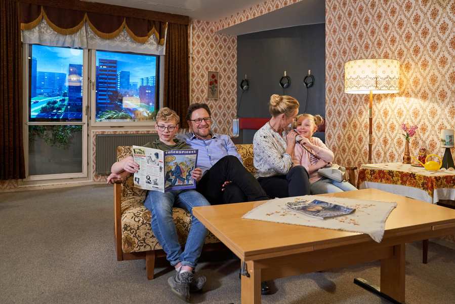 Wohnzimmer im DDR Museum mit Familie auf dem Sofa